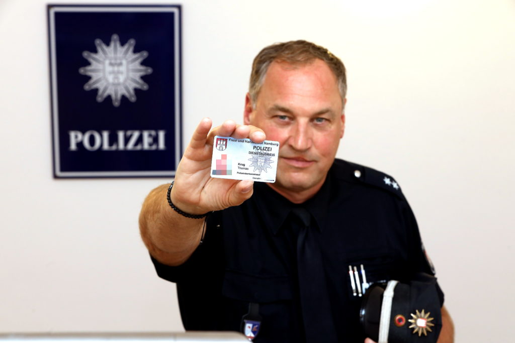 Polizist Thomas Krug zeigt seinen Dienstausweis