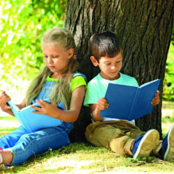 Lesende Kinder vor einem Baum