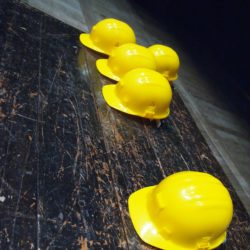 five yellow hard hats on gray surface