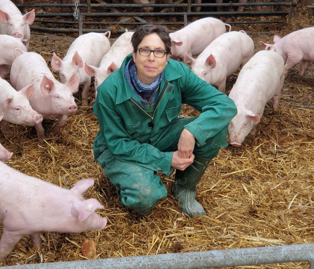 Ulrike SchreUlrike Schreiber umgeben von schweinischen Glücksbringern auf dem Bio-Gut Wulksfelde