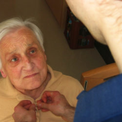Pfleger hilft altem Menschen beim Anziehen